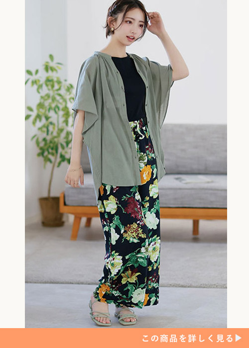 黒トップス×黒の花柄ロング丈タイトスカートにカーキのシアーブラウスを羽織る女性