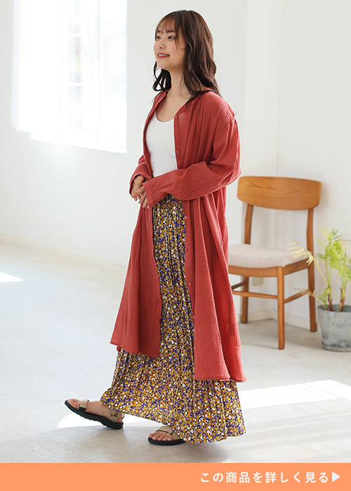 白トップス×花柄ロングスカートにオレンジのシアーシャツチュニックを羽織る女性