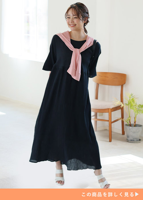 黒のワンピースを着て、ピンクのトップスを肩に巻く女性