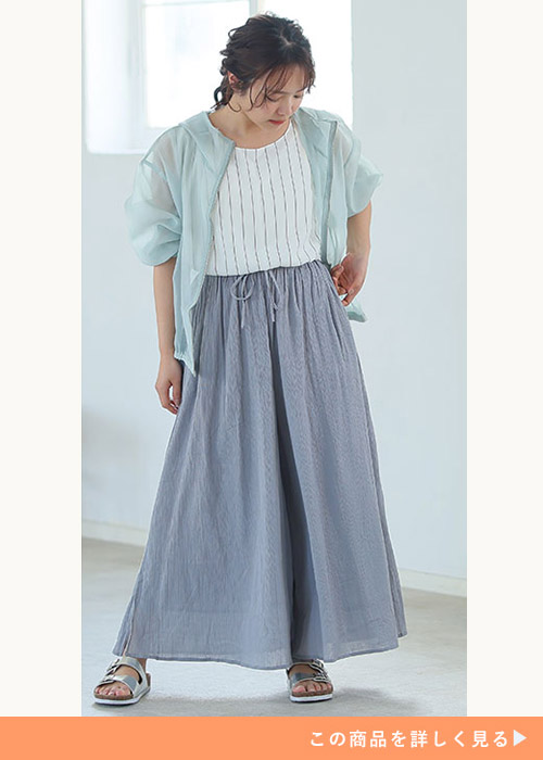 白のストライプ柄トップス×ライトグレーのスカンツに、水色のシアーブルゾンを着る女性