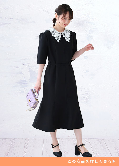 ブラックのレース襟ワンピースにミニバッグとストラップパンプスを合わせる女性