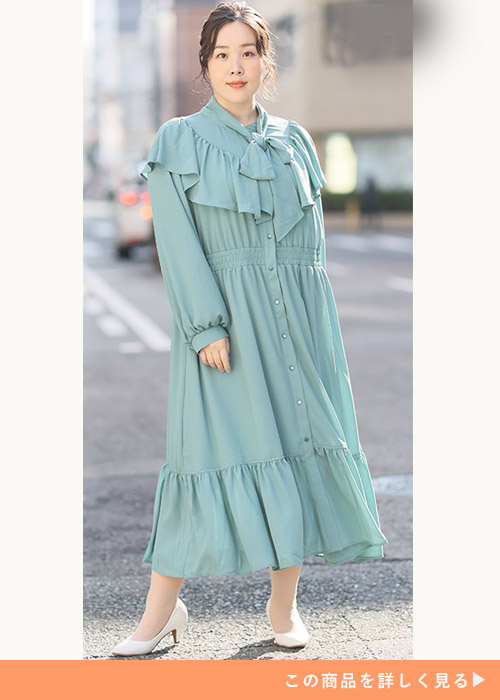 ターコイズのフリルワンピースを着て白いパンプスを履く女性