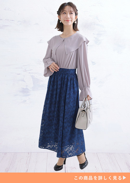 グレージュのビッグカラーのブラウスにネイビーのレーススカートを合わせる女性