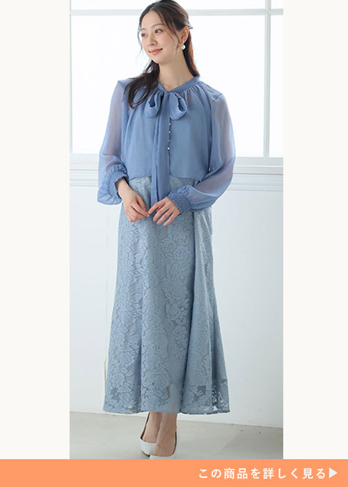 グレーのキャミワンピースにバックリボンシースルーブラウスを合わせる女性