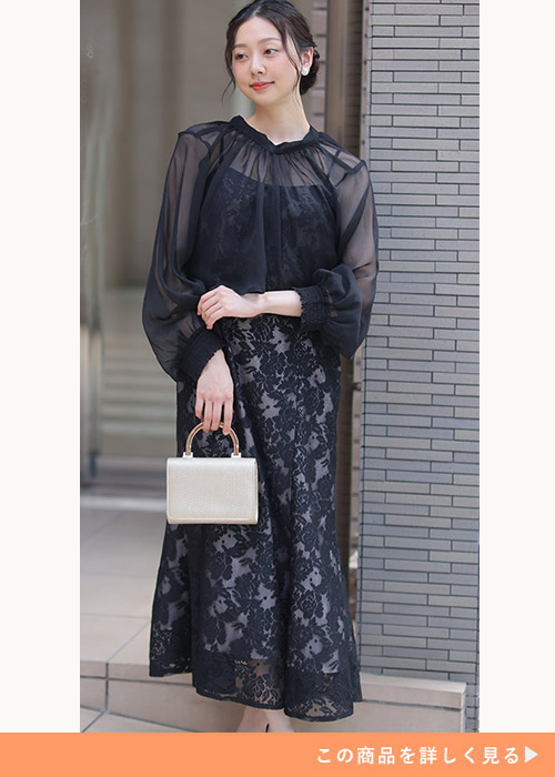 ブラックの総レースキャミワンピにシースルーのトップスをレイヤードする女性