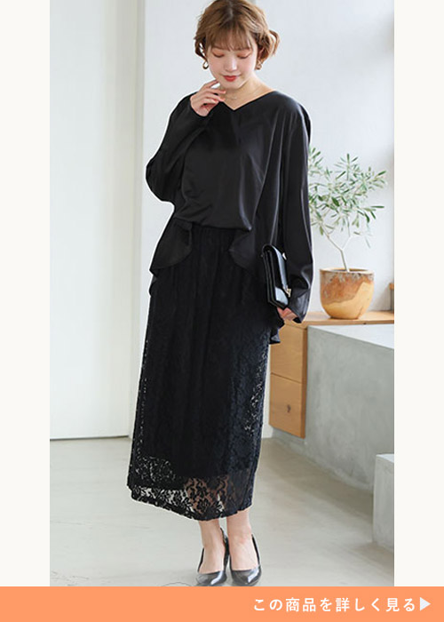 ブラックのドッキングレースワンピースにブラックのパンプスとバッグを合わせる女性