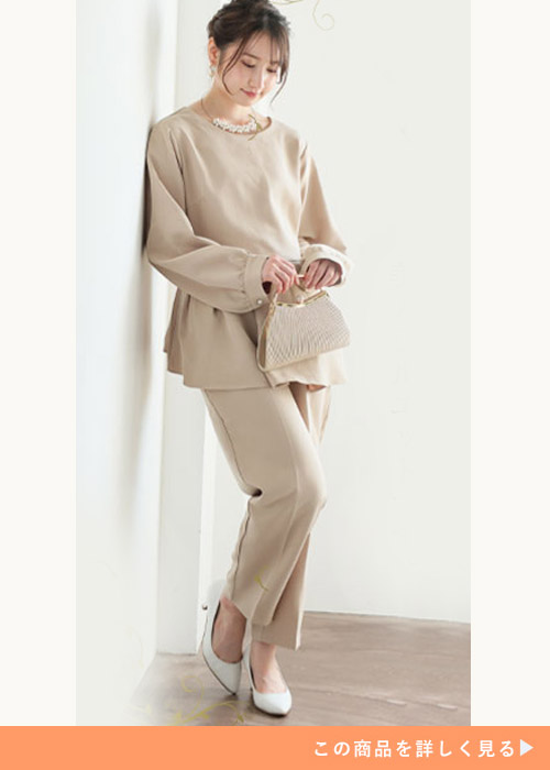 ベージュのウエストタックのトップスにセットのテーパードパンツを履く女性