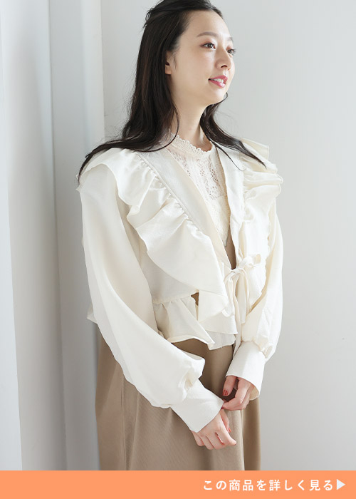 ライトブラウンのワンピースにベージュのフリルボレロを羽織る女性