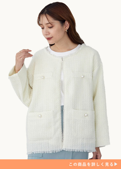 ホワイトのツイードジャケットにホワイトのインナーとブルーのボトムを合わせる女性