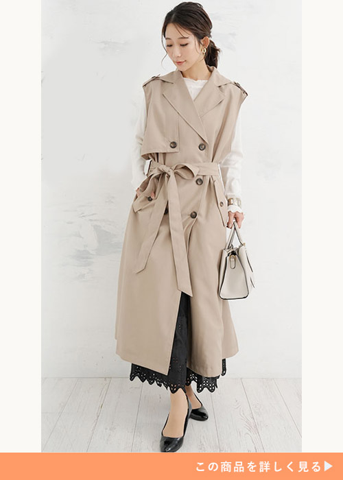 白トップス×黒のペチパンツに、ライトベージュのノースリトレンチコートを羽織る女性