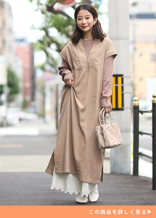 ベージュトップスにワンピースを重ね着して、インナーに白のレースのペチパンツを履く女性