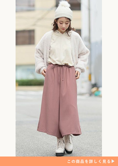 白パーカ×ピンクのスカーチョに、白カーディガンを羽織る女性