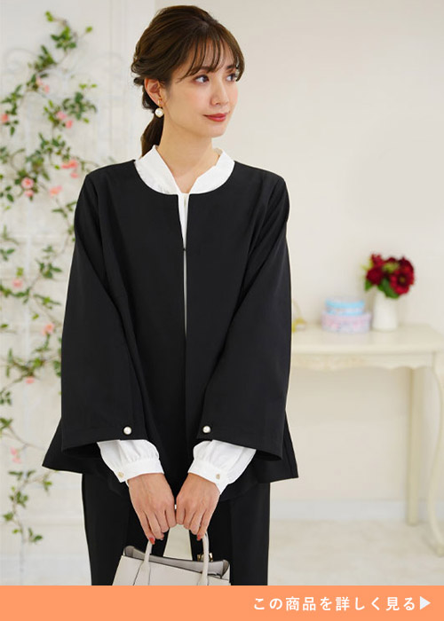ブラックのノーカラージャケットとのパンススーツにホワイトブラウスを合わせる女性