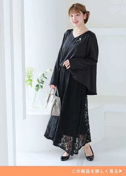 ブラックのサテンのトップスとレーススカートのドッキングワンピースを着る女性