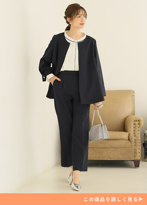 ブラックのノーカラージャケットとテーパードパンツのコーデにシルバー小物を合わせる女性