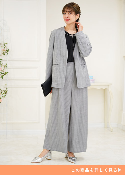 グレーのジャケットとワイドパンツのスーツにブラックのインナーを合わせる女性