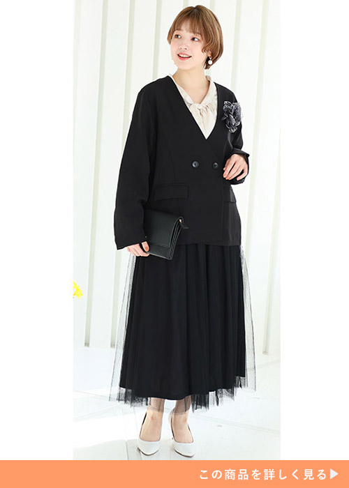 ブラックのダブルボタンのジャケットにブラックチュールスカートを履く女性