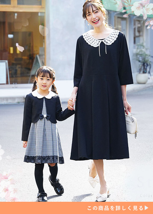 付け襟がセットのブラックの九分袖丈ワンピースにホワイトパンプスを履く女性