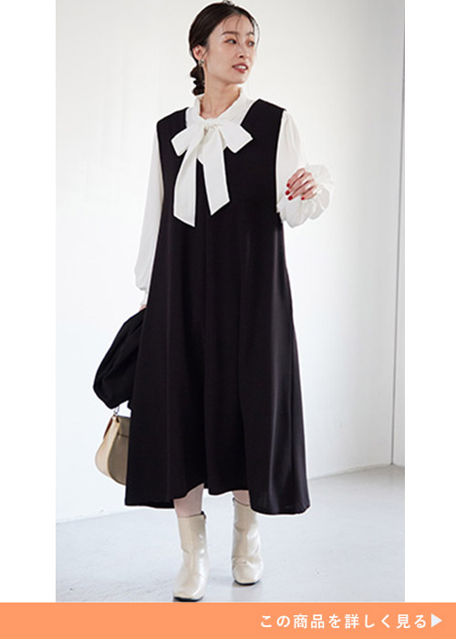 ブラックジャンパースカートとホワイトブラウスのコーデにホワイトブーツを履く女性