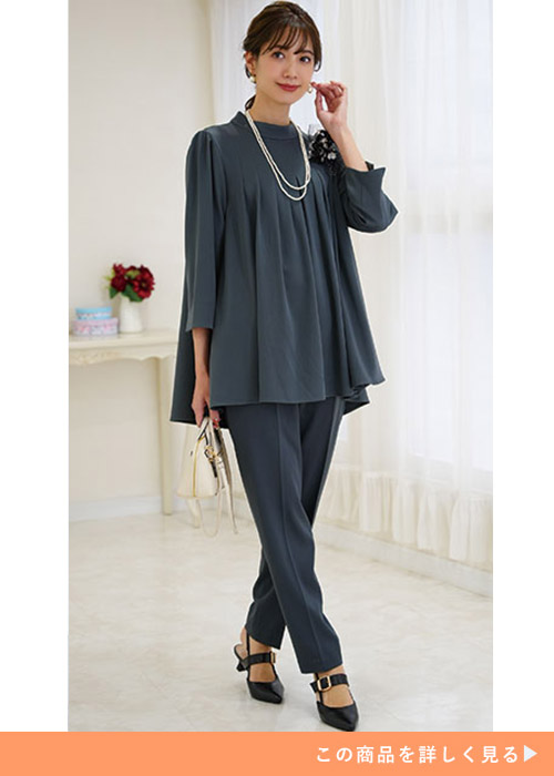 グレーのバックパール付きトップスとパンツのセットアップにパンプスを履く女性