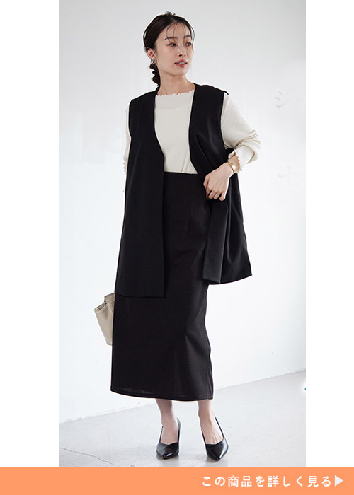 ブラックのジレとナロースカートのカセットスーツにブラックパンプスを履く女性