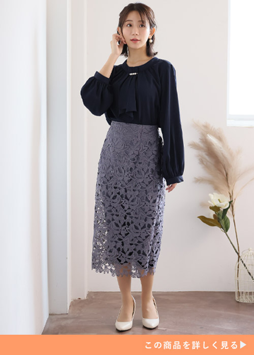 ブラックのボウタイブラウスにグレーのレースタイトスカートを履く女性