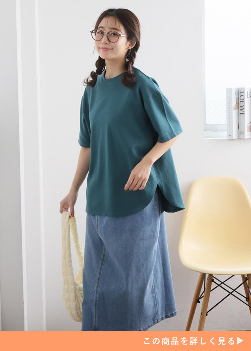グリーンの裾ラウンドTシャツ×デニムスカートを着る女性