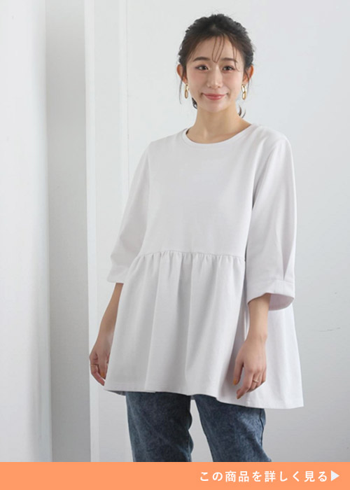 白のペプラムトップス×デニムパンツを着る女性