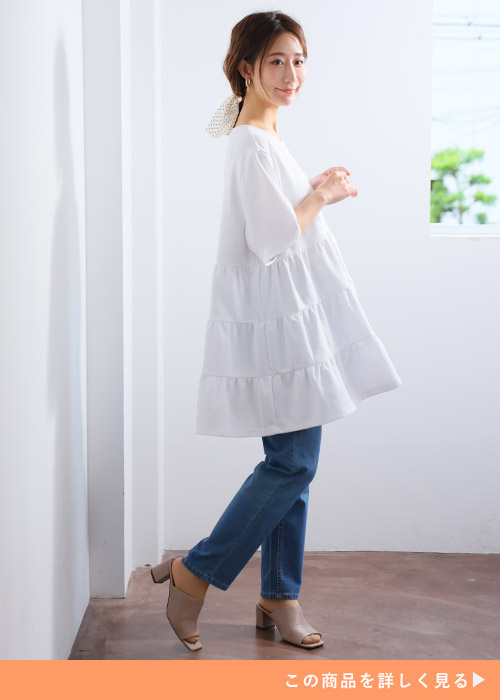 「ハッピーさらりん」の白ティアードチュニック×デニムパンツを着る女性