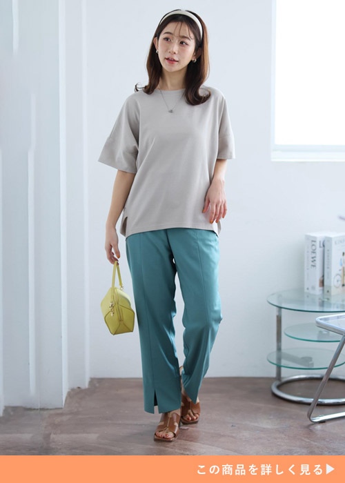 ベージュのコクーントップス×グリーンのパンツを着る女性