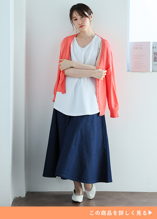 「ハッピーさらりん」の白タンクトップ×ネイビースカートに、ピンクのカーディガンを羽織る女性