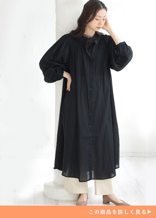 黒トップス×アイボリーパンツに、黒のシアーシャツワンピースを着る女性