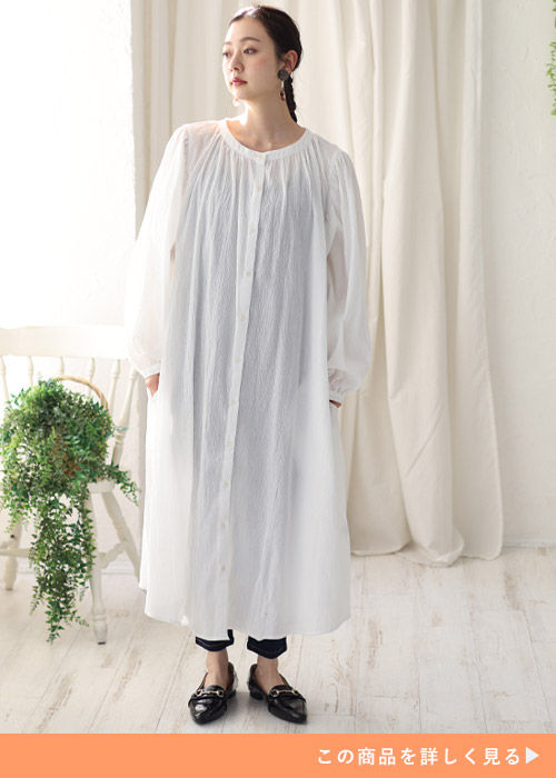 白のシャツワンピース×黒のパンツを着る女性