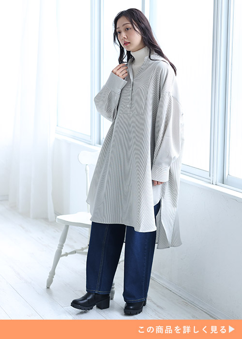 白タートルネックニット×デニムパンツに、カーキのストライプ柄シャツワンピースを重ね着する女性