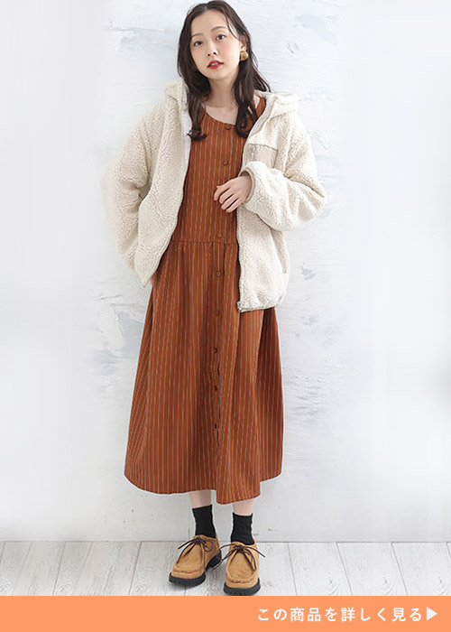 ブラウンのストライプ柄シャツワンピースに白のボアジャケットを羽織る女性