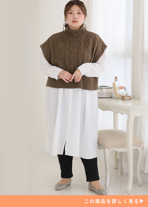 白のシャツワンピ×ブラウンのニットベストに、黒のスリムパンツを履く女性