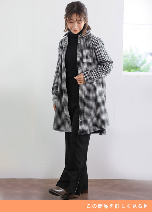 黒のタートルネックニット×黒パンツに、ギンガムチェック柄のシャツワンピースを羽織る女性