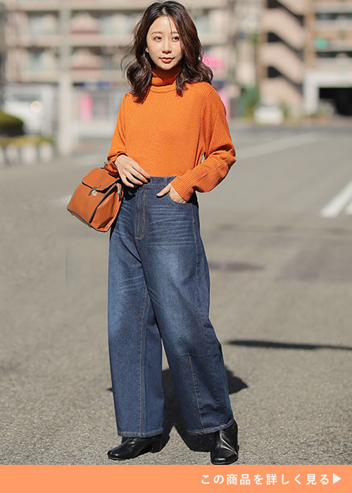 オレンジのタートルネックニット×ネイビーのデニムワイドパンツを履く女性