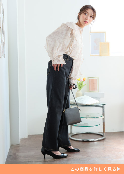 フリルブラウス×黒のワイドデニムパンツを着る女性