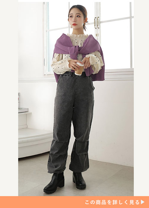 白のドット柄シャーリングブラウス×黒デニムのパラシュートパンツを着る女性