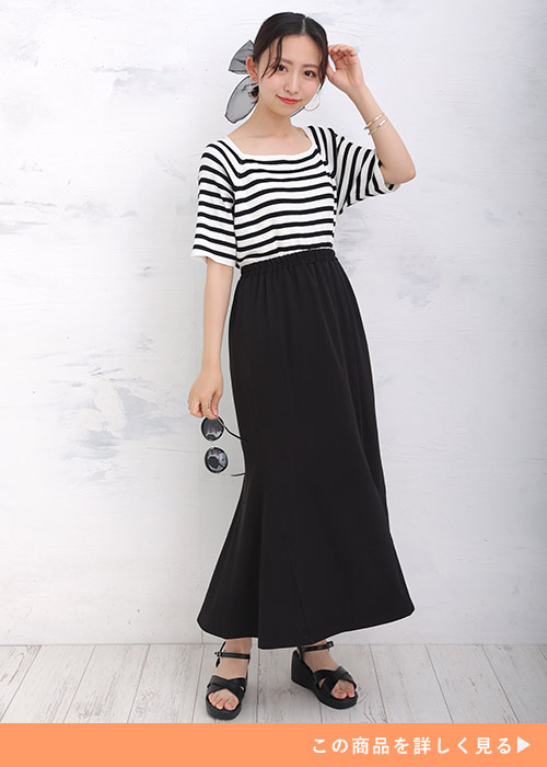 ホワイト×ブラックのボーダートップスとマーメイドスカートのコーデにブラックサンダルを履く女性