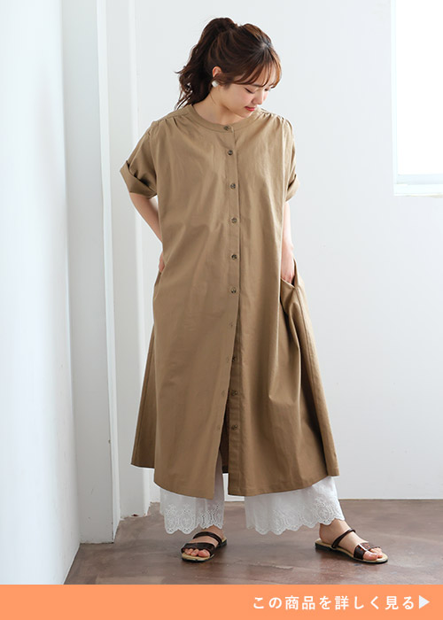 ベージュのシャツワンピースとホワイトレースパンツのコーデにブラックサンダルを履く女性