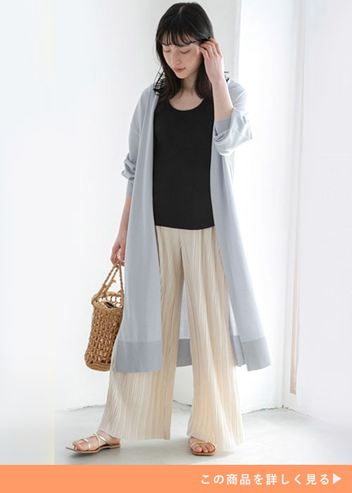 ブラックトップスとホワイトパンツにブルーグレーのロングカーデを羽織る女性