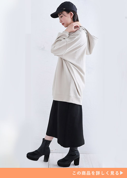 ベージュのビッグパーカとタイトスカートのコーデにブラックブーツを履く女性