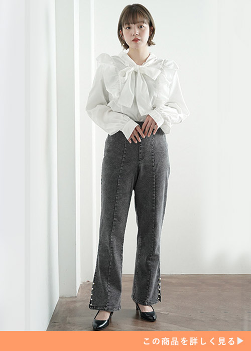 ブラックのデニムパンツとホワイトブラウスのコーデにブラックパンプスを履く女性