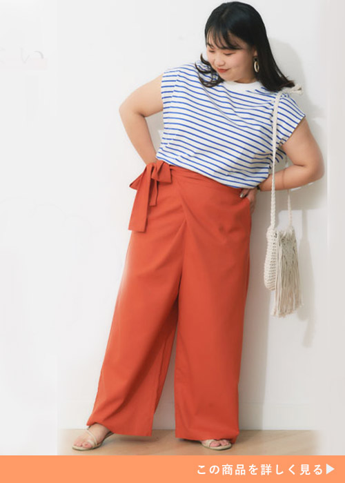 サマーオレンジのワイドパンツとボーダートップスのコーデにサンダルを履く女性