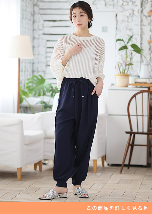 ネイビーのジョガーパンツとホワイトシアートップスにシルバーのミュールを履く女性