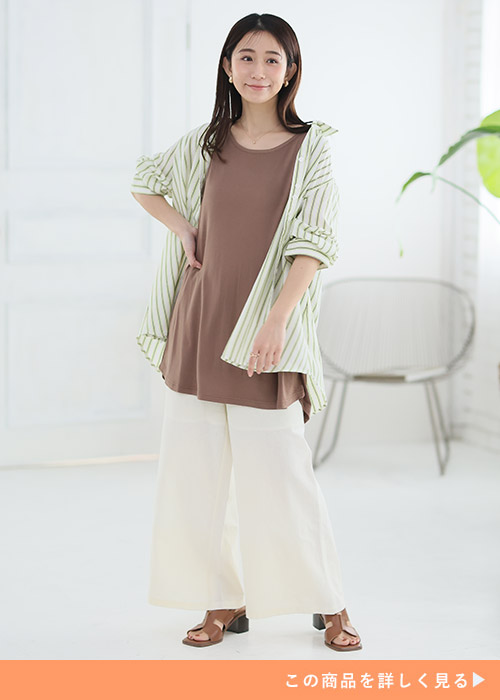 ブラウントップスとホワイトパンツのコーデにストライプリネンシャツを羽織る女性