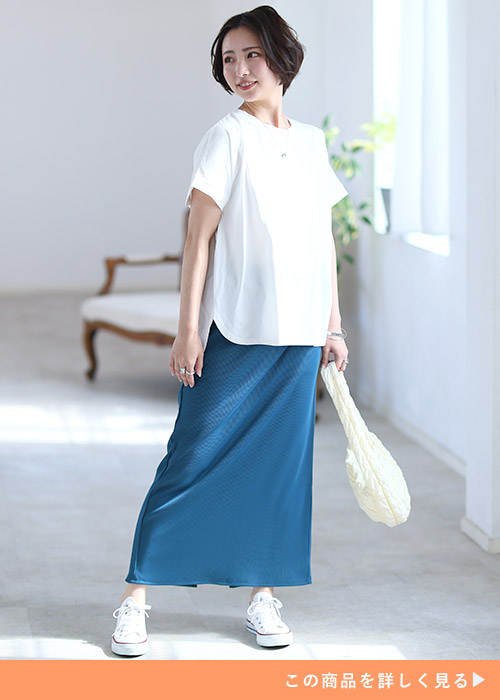 ホワイトのバックZIPカットソーとブルーのタイトスカートのコーデに白スニーカーを履く女性