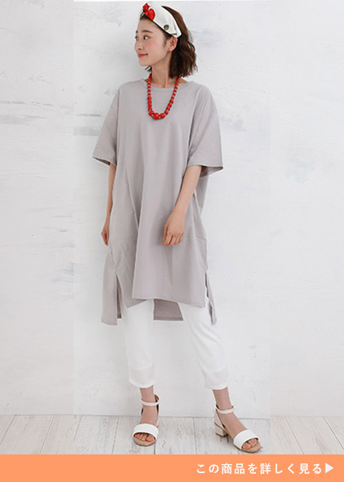 グレージュのTシャツワンピとホワイトパンツのコーデに白サンダルを履く女性